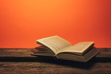 Eski bir meşe ahşap masa ve mercan turuncu duvar arka plan arkasında eski kitap.