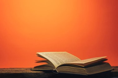 Eski bir meşe ahşap masa ve mercan turuncu duvar arka plan arkasında eski kitap.