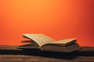 Eski bir meşe ahşap masa ve mercan turuncu duvar arka plan arkasında eski kitap.