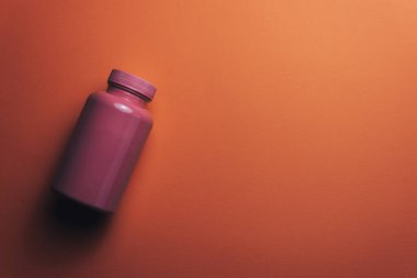 Güzel bir mercan turuncu arka plan üzerinde güzel pembe şişe ve pembe hapları. 