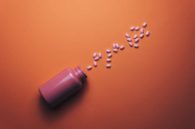 Güzel bir mercan turuncu arka plan üzerinde güzel pembe şişe ve pembe hapları. 