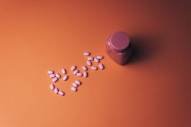 Güzel bir mercan turuncu arka plan üzerinde güzel pembe şişe ve pembe hapları. 