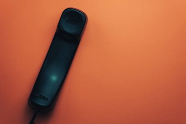 Güzel bir mercan turuncu arka plan üzerinde siyah telefon.