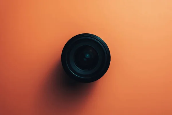 Black Camera Lens on a beautiful  coral orange background.