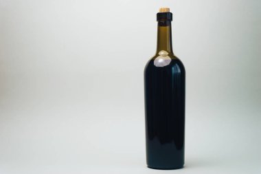 Eski bir meşe ahşap masa ve gri arka plan üzerinde kırmızı şarap Şişesi.