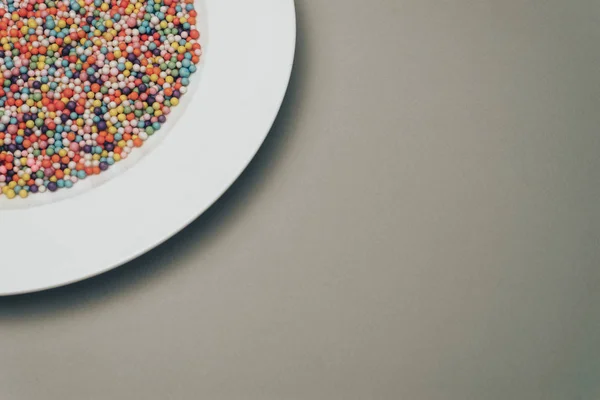 White plate with color preparations (vitamins, dyes, flavor enhancers, nutritional supplements, innovative technologies, candy sweets) on a gray background.