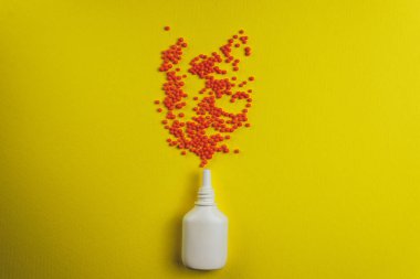 White nose spray with particle aerosol spray made by red preparations on a yellow background.