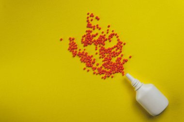 White nose spray with particle aerosol spray made by red preparations on a yellow background.
