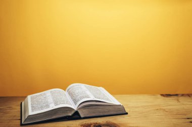 Kahverengi ahşap bir masanın üzerinde İncil. Beutiful turuncu duvar arka plan.