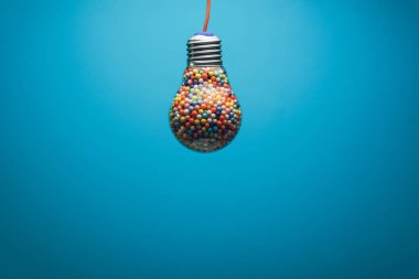 Yaratıcı ampul arkasında mavi bir arka plan üzerinde çok renkli topu ile dolu. En iyi fikir konsepti.