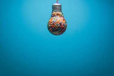 Yaratıcı ampul arkasında mavi bir arka plan üzerinde çok renkli topu ile dolu. En iyi fikir konsepti.