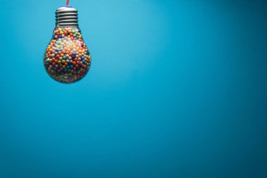 Yaratıcı ampul arkasında mavi bir arka plan üzerinde çok renkli topu ile dolu. En iyi fikir konsepti.