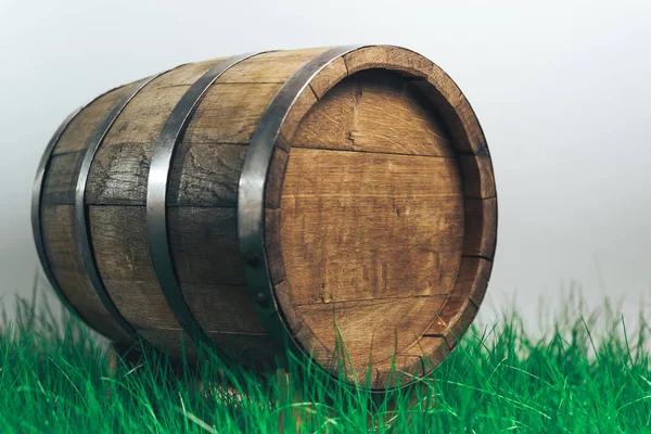 灰色の背景に草の中の古いウーデン樽 — ストック写真