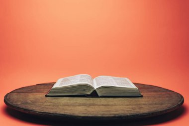 İncil ve haç boncukları eski yuvarlak masada. Güzel mercan turuncu arka plan. Din kavramı.