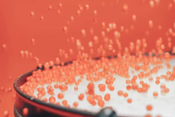 Colored balls bounces off drum in shockwave pattern. Beautiful coral orange background.