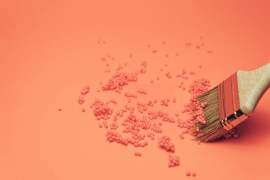 Mercan turuncusu arka planda Yaratıcı Fırça ve renkli toplar.