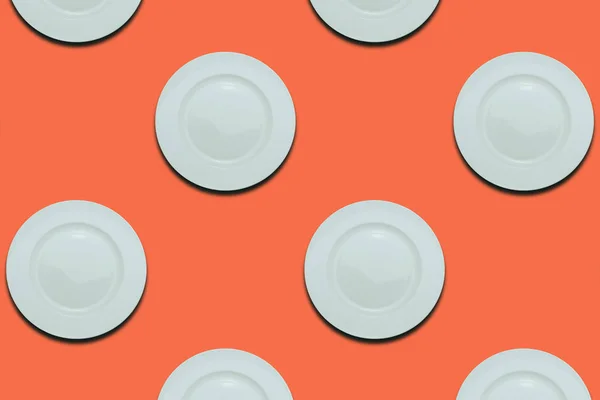 White plates on a coral orange flat background. Copy space