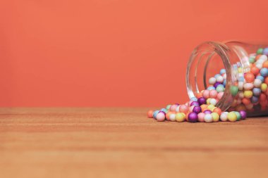 Çok renkli preparatlar Küçük şişe (vitaminler, boyalar, lezzet arttırıcılar, besin takviyeleri, yenilikçi teknolojiler, şeker tatlılar) Mavi ahşap masa ve mercan turuncu arka plan. 