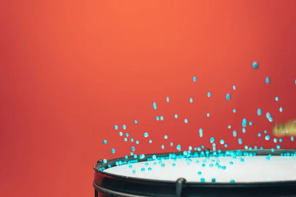 Colored balls bounces off drum in shockwave pattern. Beautiful red background.