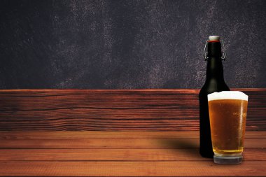 Ahşap eski bir meşe masasında bir bardak bira. Güzel duvar arka planı.
