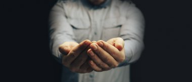 Koyu bir arka plan üzerinde erkek el açık avuç içi el hareketi.