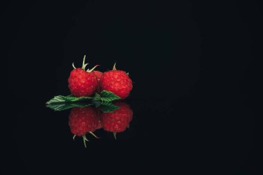 Siyah cam masa koyu arka plan üzerinde Güzel üç taze ahududu.