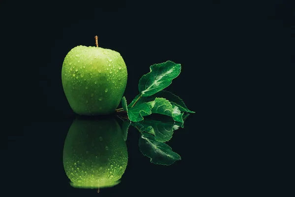Green apple on a black glass table background.