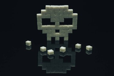 Siyah cam masa arka plan üzerinde şeker küpleri ile Kafatası. Kavram tatlı öldürmek veya sağlıksız diyet .