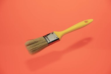 Bir mercan turuncu ve sarı arka plan üzerinde yeni boya fırçası.