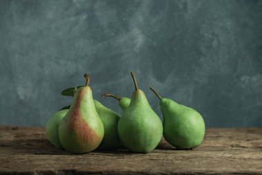 Eski bir meşe ahşap masa üzerinde taze yeşil armut, güzel gri duvar arka plan.