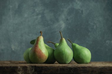 Eski bir meşe ahşap masa üzerinde taze yeşil armut, güzel gri duvar arka plan.