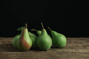 Eski bir meşe ahşap masa üzerinde taze yeşil armut, güzel siyah arka plan.