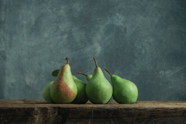 Eski bir meşe ahşap masa üzerinde taze yeşil armut, güzel gri duvar arka plan.
