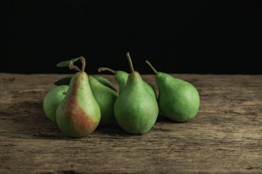 Eski bir meşe ahşap masa üzerinde taze yeşil armut, güzel siyah arka plan.