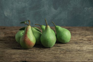 Eski bir meşe ahşap masa üzerinde taze yeşil armut, güzel gri duvar arka plan.