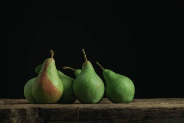 Eski bir meşe ahşap masa üzerinde taze yeşil armut, güzel siyah arka plan.