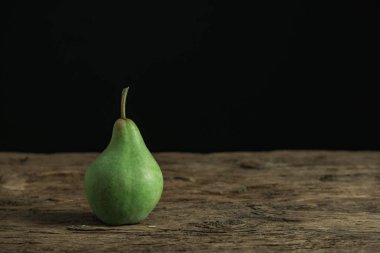 Eski bir meşe ahşap masa üzerinde taze yeşil peara, güzel siyah arka plan.