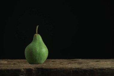 Eski bir meşe ahşap masa üzerinde taze yeşil peara, güzel siyah arka plan.