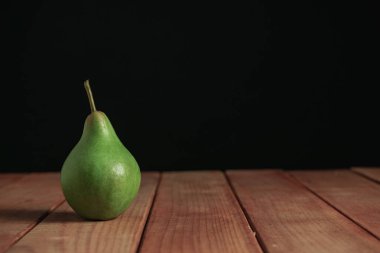 Kırmızı ahşap masa üzerinde taze yeşil armut, güzel siyah arka plan.