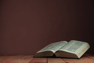 Eski ahşap bir masaüzerinde Kutsal Kitap'ı açın. Güzel kırmızı duvar backgroround. Din kavramı.