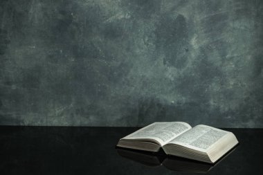 Siyah cam masanın üzerinde İncil var. Güzel gri duvar arka plan