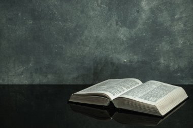 Siyah cam masanın üzerinde İncil var. Güzel gri duvar arka plan
