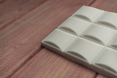 Kırmızı ahşap masa arka plan üzerinde beyaz çikolata kapatın. Makro görünümü.