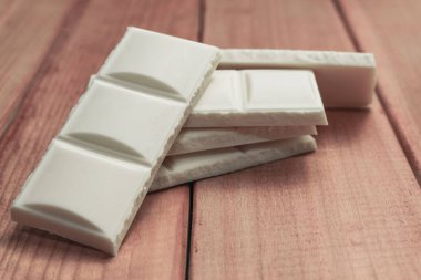 Kırmızı ahşap masa arka plan üzerinde beyaz çikolata kapatın. Makro görünümü.