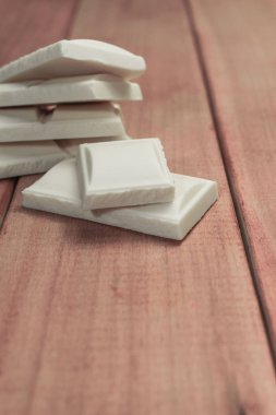 Kırmızı ahşap masa arka plan üzerinde beyaz çikolata kapatın. Makro görünümü.