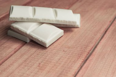 Kırmızı ahşap masa arka plan üzerinde beyaz çikolata kapatın. Makro görünümü.