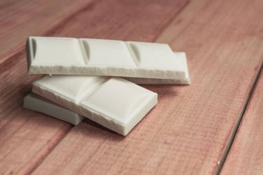 Kırmızı ahşap masa arka plan üzerinde beyaz çikolata kapatın. Makro görünümü.