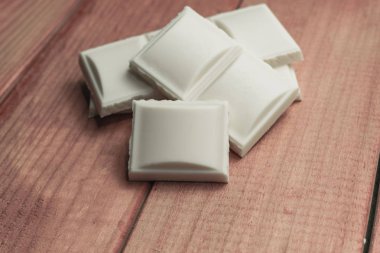 Kırmızı ahşap masa arka plan üzerinde beyaz çikolata kapatın. Makro görünümü.