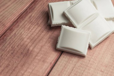 Kırmızı ahşap masa arka plan üzerinde beyaz çikolata kapatın. Makro görünümü.