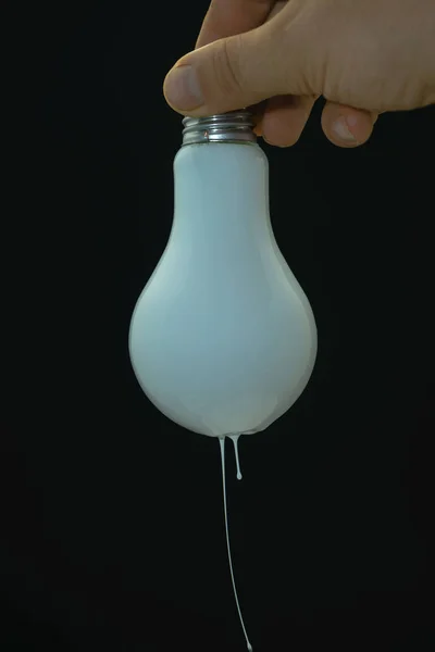 Hand Holding Big Light Bulb Dripping White Paint Black Background — Stock Photo, Image